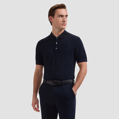 Man wearing a navy polo shirt and pants on a light gray background