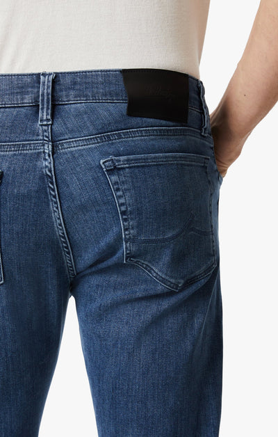 Close-up of a person wearing 34 Heritage Mid Urban dark-wash modern straight-leg jeans and a white shirt, featuring a visible black label on the waistband.