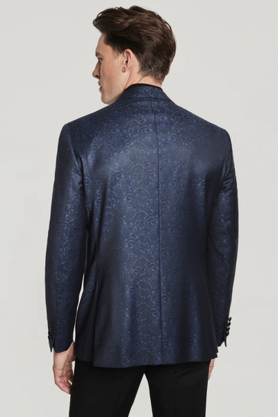 A man is seen from the back wearing the Jack Victor Navy Paisley Dinner Jacket by Ted's Clothiers with black pants, set against a plain light background.
