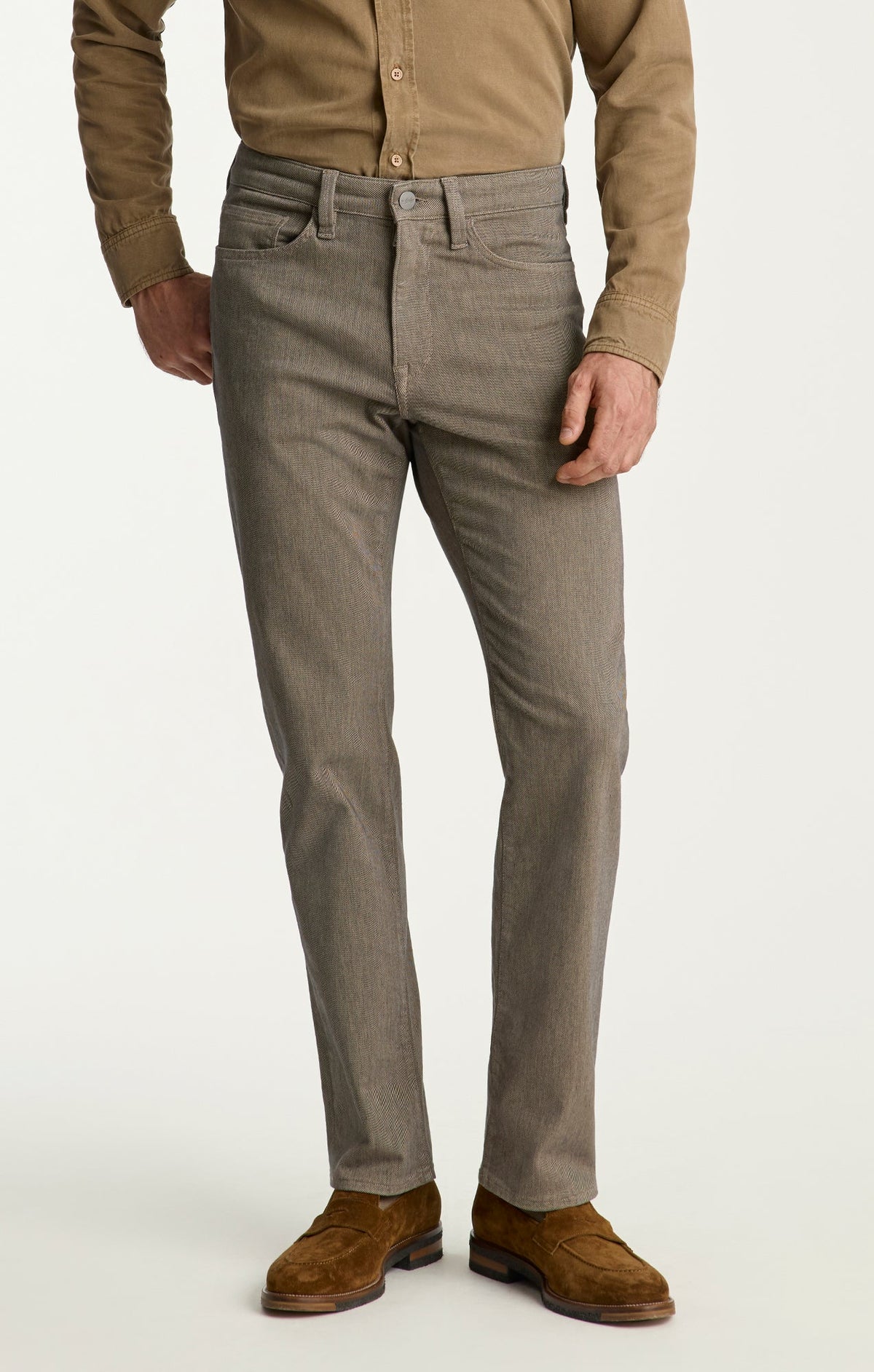 A man wearing a tan button-up shirt, 34 Heritage Charisma Diagonal Jeans Big & Tall, and brown suede shoes stands against a plain background.