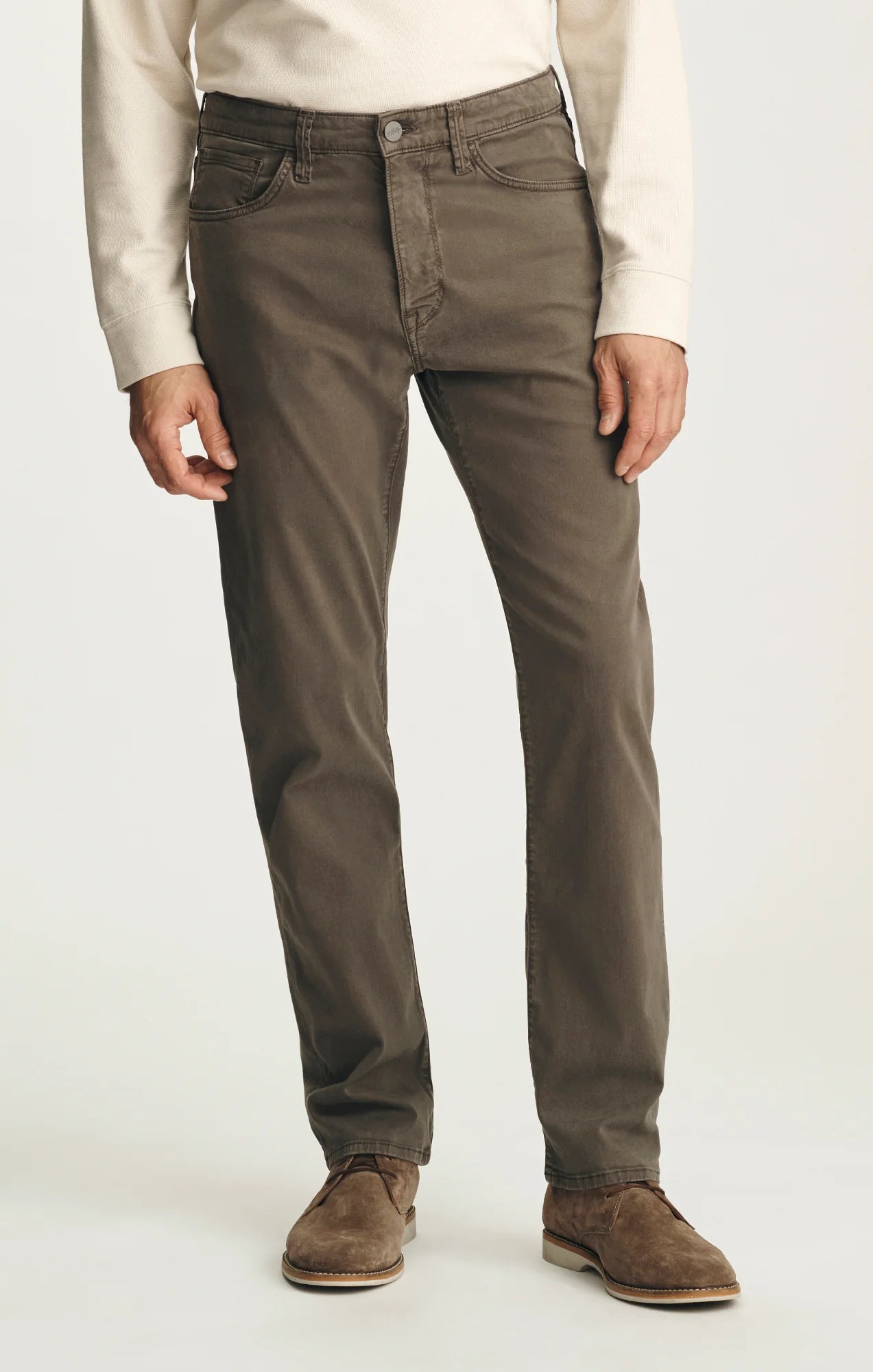 A person wears the 34 Heritage Courage Twill Pant in olive green, paired with a cream long-sleeve shirt and brown suede shoes, standing against a plain background.