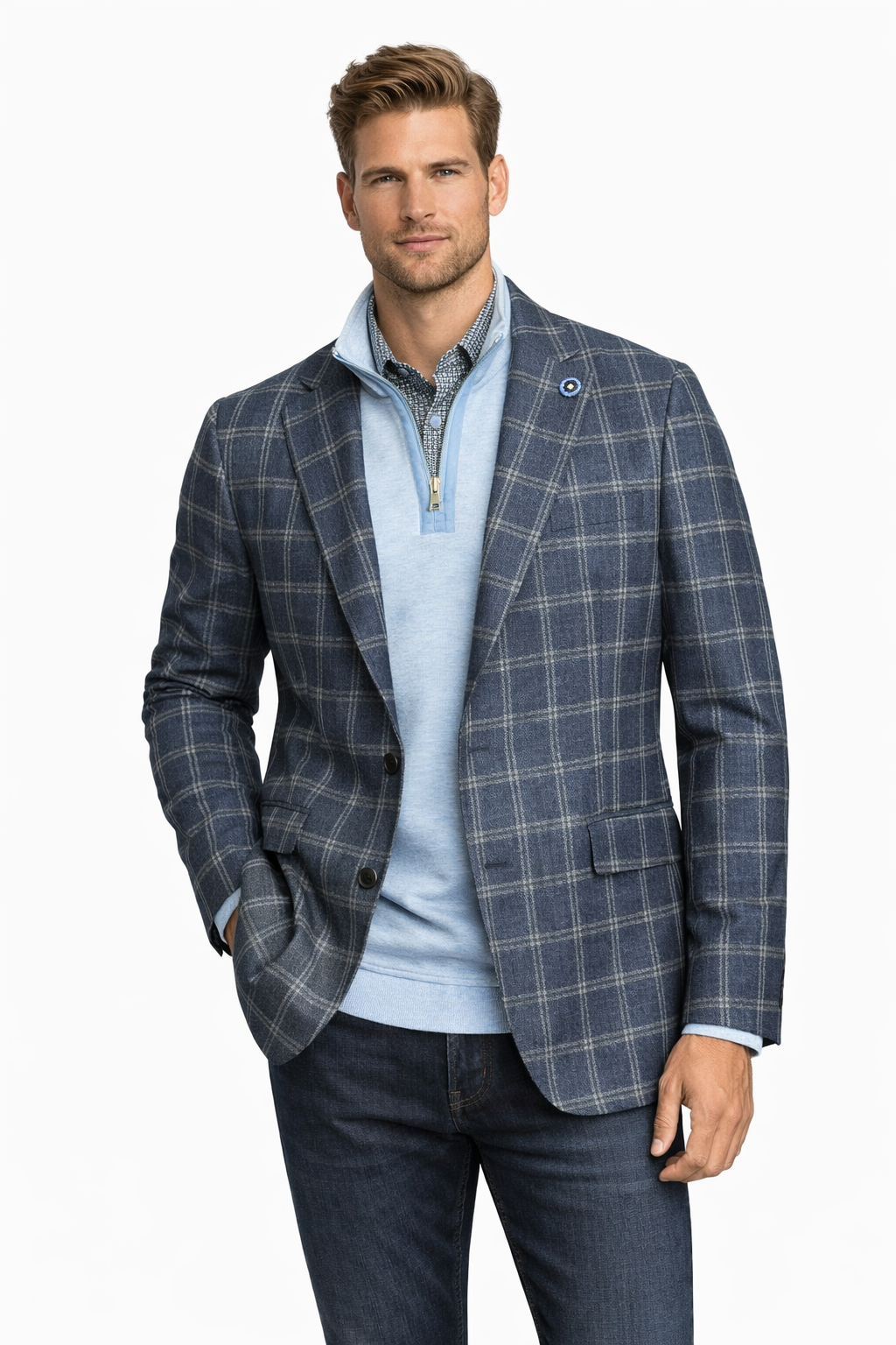 A man wearing the Hart Schaffner Marx Sport Coat 24H0081, featuring a blue plaid pattern and tailored fit, layered over a light blue quarter-zip sweater, checked shirt, and dark jeans against a plain white background.