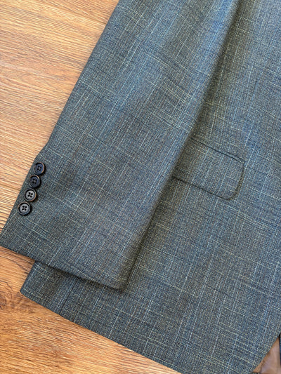 Close-up of a Hart Schaffner Marx Olive Sport Coat New York Fit (style 35H0132) sleeve with three black buttons, lying on a wooden surface.