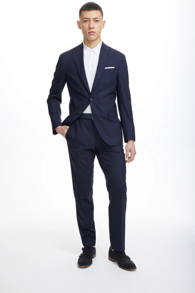 A man faces forward wearing the Jack Victor Wool Stretch Suit in navy blue by Jack Victor, paired with a white dress shirt and black dress shoes, set against a plain white background.