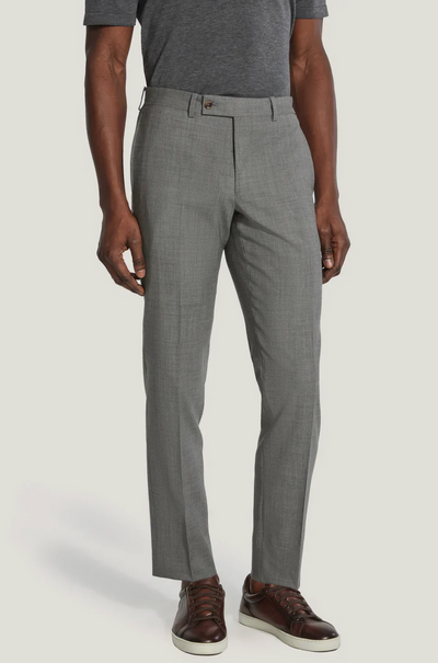 A person wearing Jack Victor Riviera Traveler Pants in gray, a dark gray short-sleeve shirt, and brown leather sneakers stands against a plain light background.