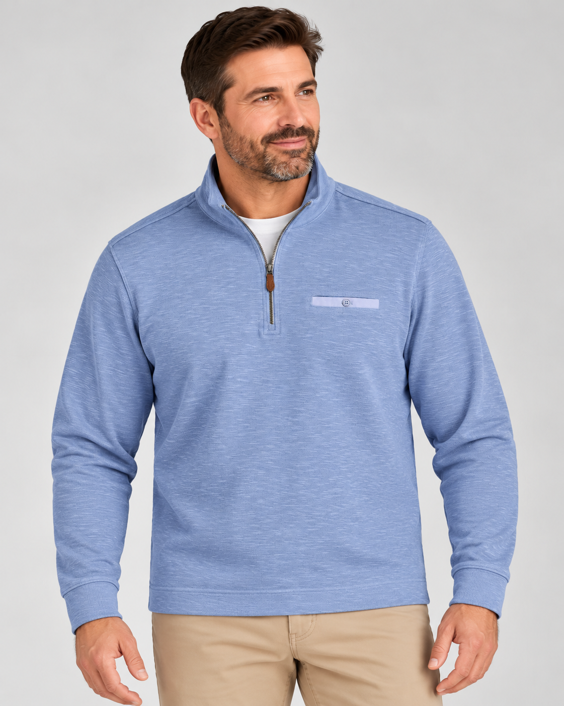 A man wearing a light blue Johnnie-O Flame Stitch 1/4 Zip Sweater Big & Tall with a small chest pocket and khaki pants.