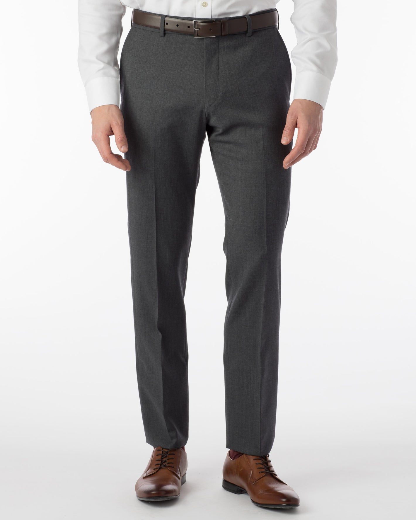 A man stands against a plain white background wearing Ballin Super 120's Comfort-EZE Big & Tall trousers in mid grey, paired with a white dress shirt, brown leather belt, and brown dress shoes.