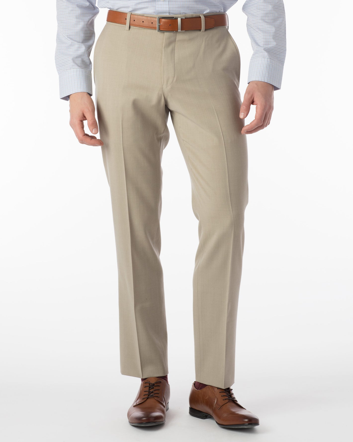 A person is shown wearing Ted's Clothiers Ballin Comfort-EZE Dress Pants in Oatmeal (Soho Modern Fit), paired with a brown belt, brown dress shoes, and a light blue checkered shirt. The image is cropped at the shoulders.