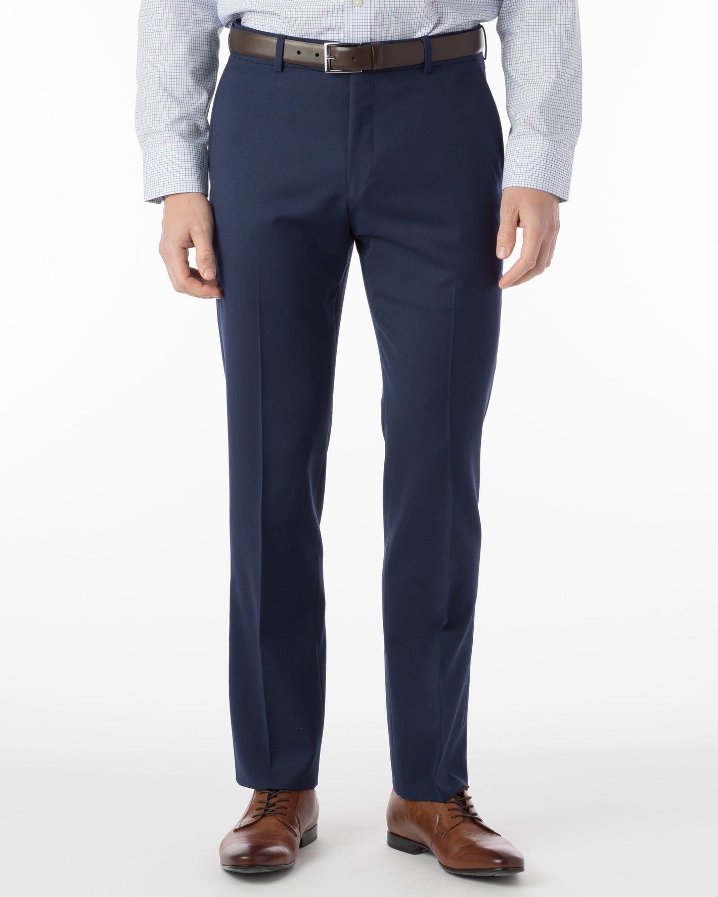 A person wearing Ballin Super 120's Comfort-EZE Big & Tall - Mariner navy pants, a light patterned shirt, brown belt, and brown dress shoes stands against a white background.