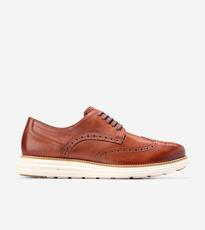 The Cole Haan Grand Remastered Wingtip Oxford by Ted's Clothiers features a brown brogued leather upper, white FlowerFoam midsole, and classic wingtip details—shown in profile on a plain background.