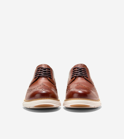 The Cole Haan Grand Remastered Wingtip Oxford from Ted's Clothiers features a brogued brown leather upper, cushioned FlowerFoam midsole, and white soles, shown from the front on a plain white background.