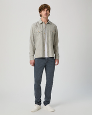 Man wearing a light gray shirt and dark blue jeans on a white background