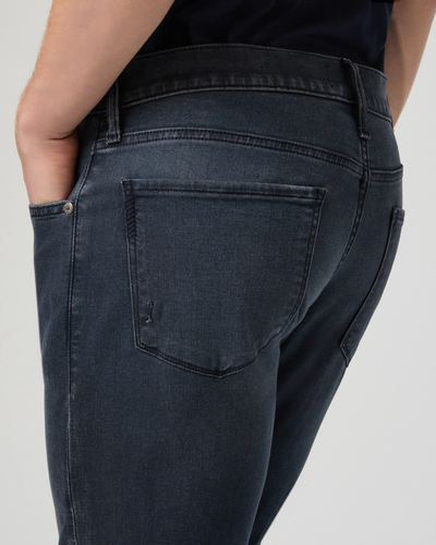 Dark blue jeans being worn on a plain background