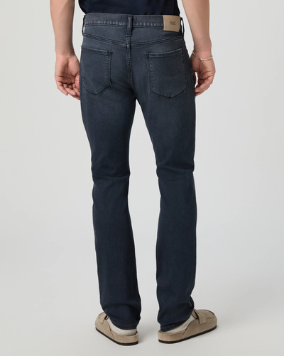 Person wearing dark blue jeans on a plain background