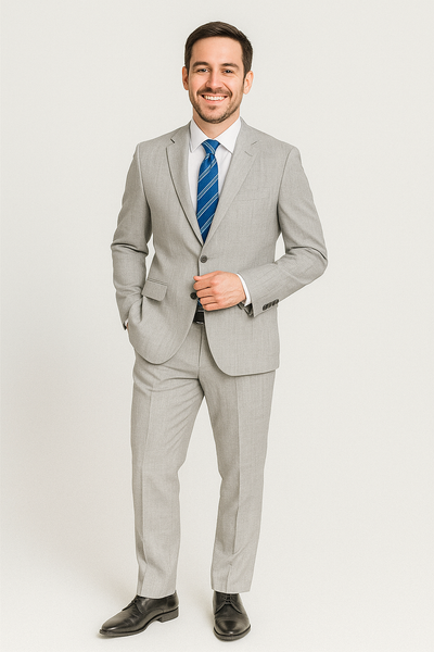 A man in a Paul Betenly Solid Suit - Slim Fit by Paul Betenly stands smiling with one hand in his pocket, wearing a white shirt and blue striped tie against a plain background.