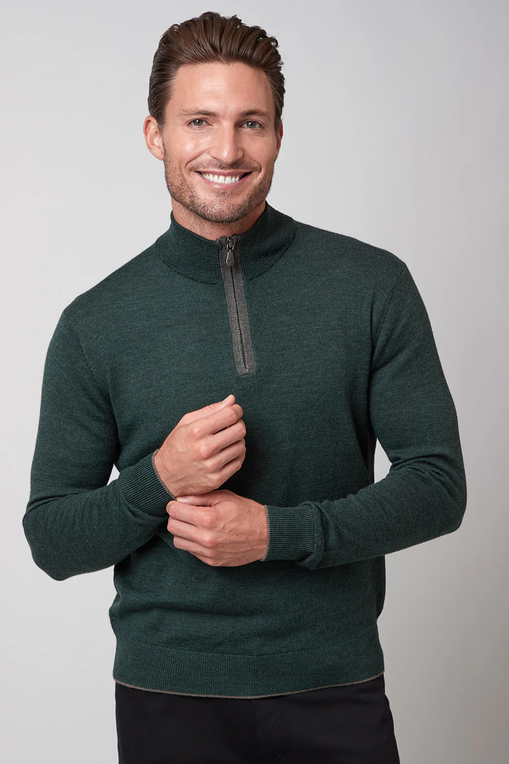 Man wearing a green sweater with a zipper on a gray background