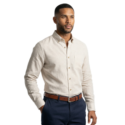 Man wearing a light-colored button-up shirt and dark pants on a white background