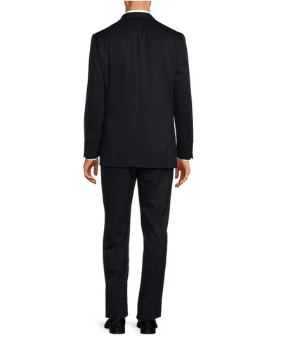 A man stands facing away from the camera, wearing a Hart Schaffner Marx Chicago Fit Suit Big & Tall, black dress shoes, and a white shirt—a refined option in men's luxury workwear.