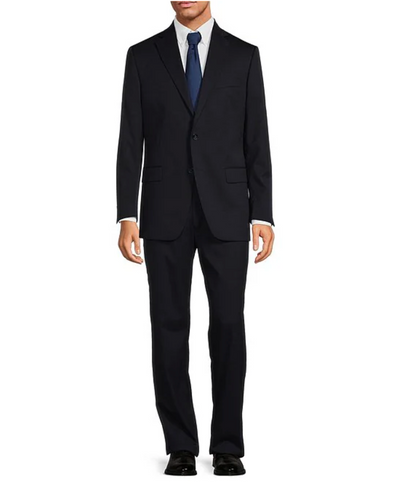 A man in a Hart Schaffner Marx Chicago Fit Suit Big & Tall, white dress shirt, blue tie, and black dress shoes stands against a white background—an excellent example of upscale men's workwear from Hart Schaffner Marx.