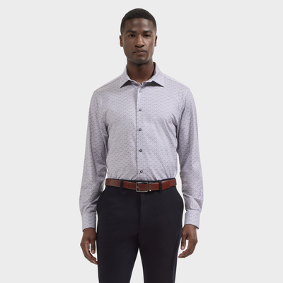 A man wearing the Bugatchi James Medallion Sport Shirt KF9062K60, renowned for its breathable and wrinkle-resistant OoohCotton fabric, paired with dark trousers and a brown belt, stands against a plain white background.