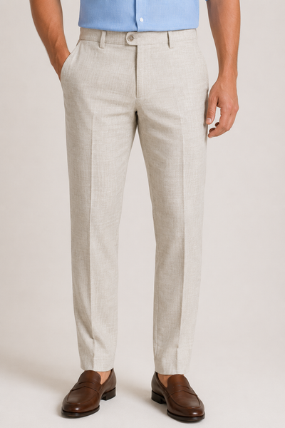 A man wears Jack Victor Voyageur Linen Pants R646 by Jack Victor in light beige, paired with a blue dress shirt and brown loafers, standing with hands in pockets against a plain background.
