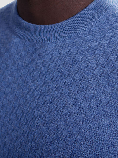 Close-up of a person wearing the Bugatchi Basketweave Crew Neck Sweater HH202CN1 by Bugatchi, featuring a blue geometric basketweave pattern, lightweight knit, and stylish round neckline.