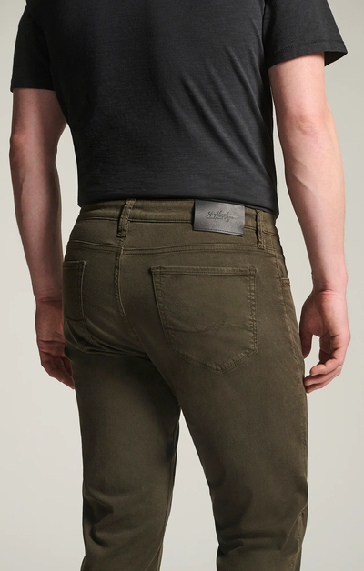 A person is shown from the back wearing 34 Heritage Courage Twill Straight Leg Pants in cactus green and a black t-shirt, with the 34 Heritage brand patch visible on the waistband.