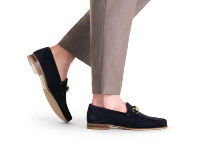 A person wearing tan pants and the Magnanni Giancarlo Moc Toe Bit Loafer in navy blue suede, featuring gold bit detail and hand-stitched accents by Magnanni, shown against a white background.