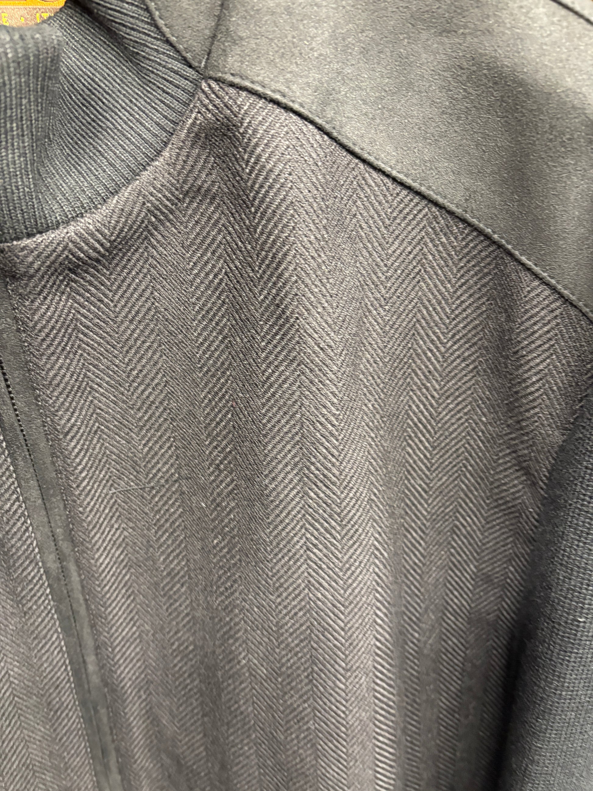 Close-up of the Enzo Nino Suede Bomber Jacket by Enzo, highlighting its dark-colored herringbone design with contrasting suede fabric on the shoulders and collar.