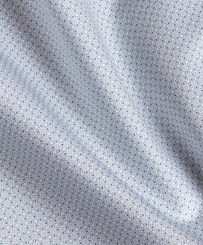 Close-up of light blue fabric featuring a small, repeating geometric print and visible folds, creating gentle shadows across the surface—reminiscent of the refined texture found in the David Donahue Micro Geometric Print Dress Shirt TBSP13203 by David Donahue.