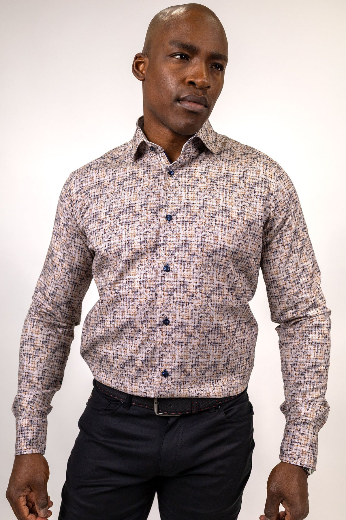 A man wears a 7 Downie St. Brown & Beige Abstract Print Sport Shirt – Big & Tall 26059 with a long-sleeved, brown and beige abstract grid pattern paired with dark trousers.
