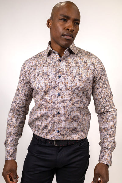 A man wears a 7 Downie St. Brown & Beige Abstract Print Sport Shirt – Big & Tall 26059 with a long-sleeved, brown and beige abstract grid pattern paired with dark trousers.
