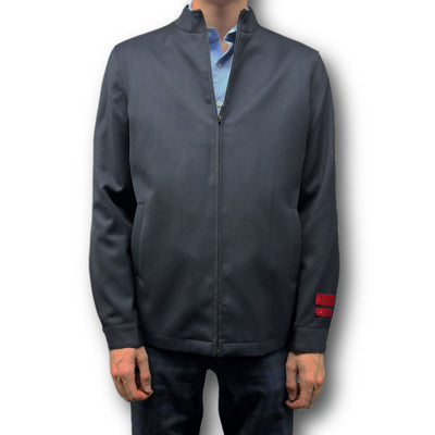 A person in the Mattarazi Coat Paolo by Mattarazi, layered over a light blue shirt and dark pants, stands against a plain white background.