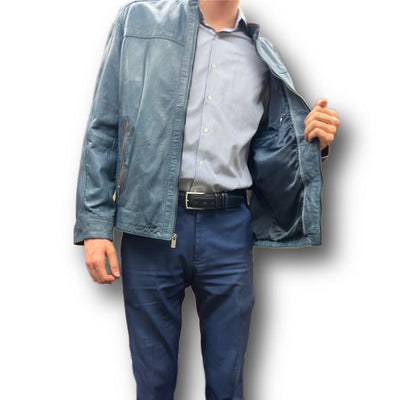 A model wears the Missani Leather Jacket 392834 in blue Italian lambskin over a striped shirt and navy pants, holding it open to show the lining. The scene is set against a white background with a subtle shadow.