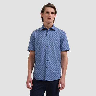 A man wears the Bugatchi Miles OoohCotton® Leaf Print Shirt JF9138F40 with dark pants, standing against a plain light gray background.