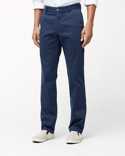 A person wearing Tommy Bahama Boracay Pant Big & Tall in blue supersoft cotton, a white button-up shirt, and light-colored slip-on shoes stands against a plain white background.