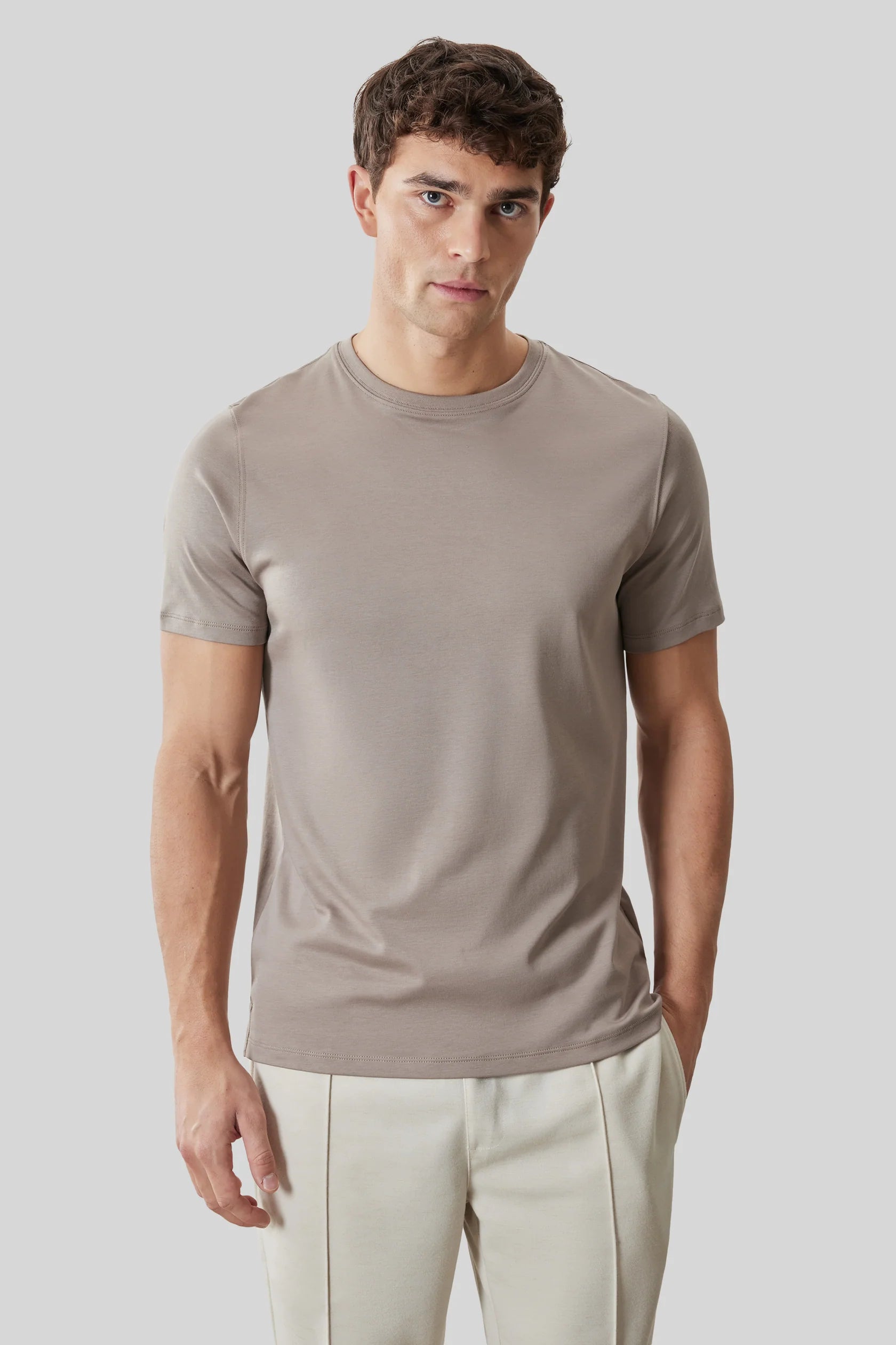 A man wearing a Robert Barakett Georgia Crew 23336 fitted taupe Pima cotton T-shirt and light beige pants stands against a plain light gray background.