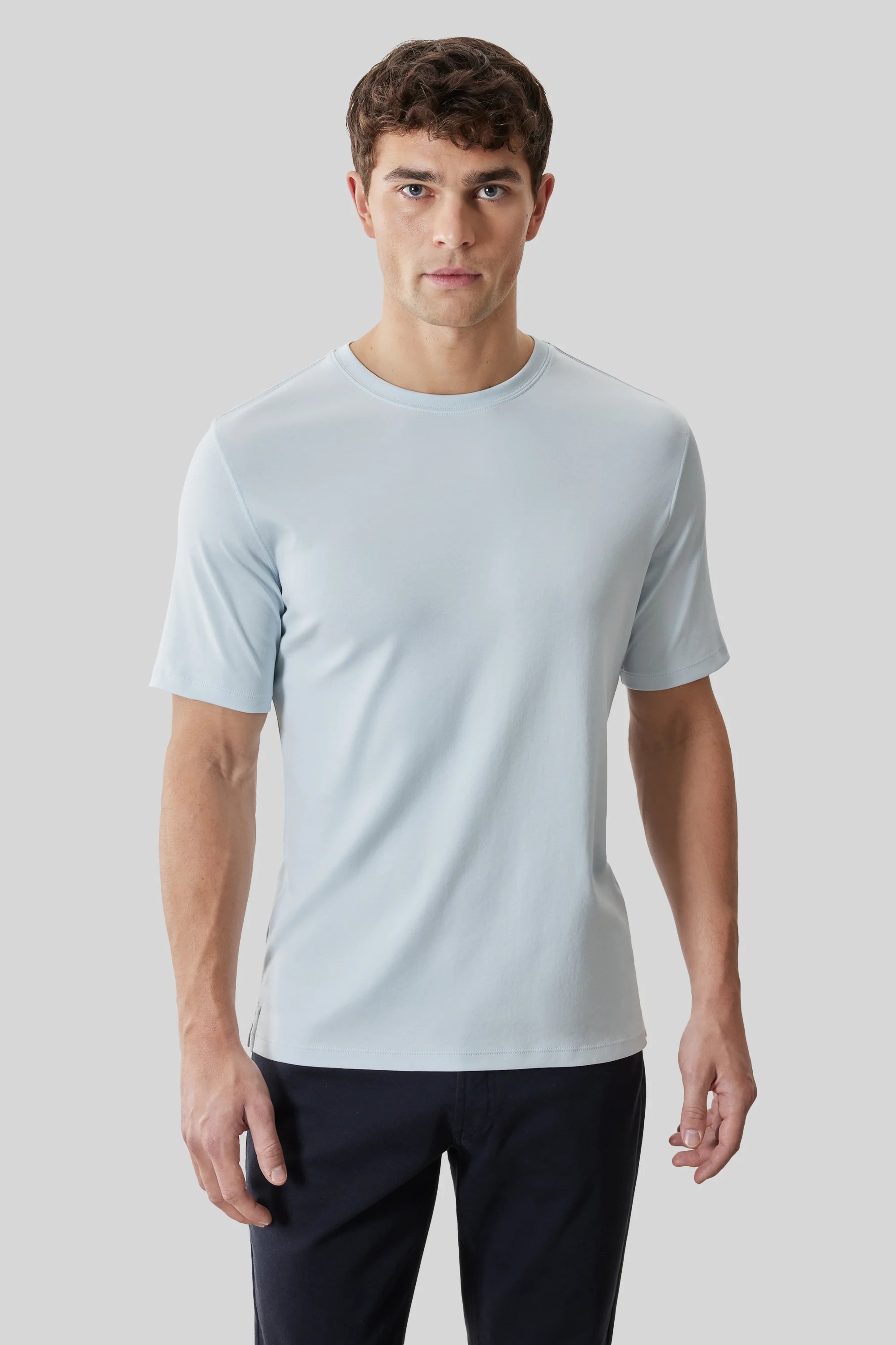 A man wearing the Robert Barakett Tee Shirt Georgia Crew 23336 in light blue and black pants stands against a plain light gray background.