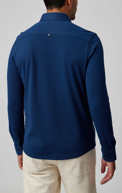 A man wearing a Stone Rose ORIGIN Long Sleeve T-Series Sport Shirt in dark blue and off-white pants is seen from the back against a plain background.