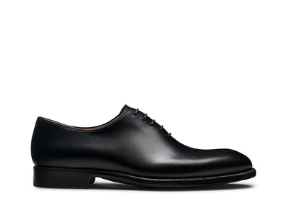 The Magnanni Hawkins Wholecut Oxford Dress Shoe by Magnanni, crafted from black calfskin leather with closed lacing, is shown from the side against a white background.