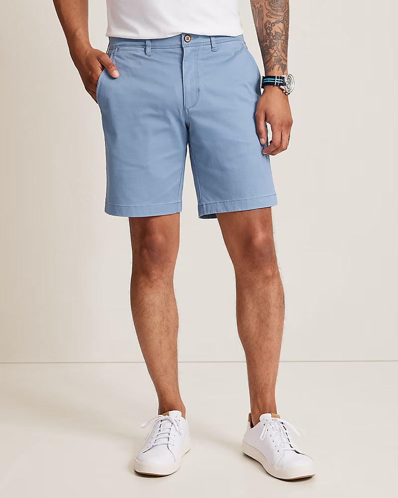 A person wears light blue Tommy Bahama Boracay Shorts Big & Tall in a soft TENCEL™ blend, paired with a watch and white sneakers, standing with hands in pockets against a plain background.