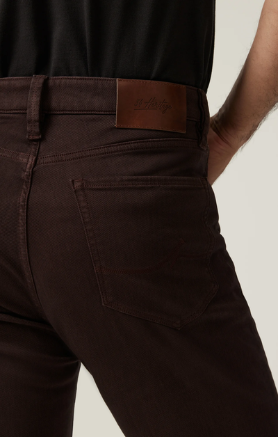 A close-up of someone wearing 34 Heritage Charisma Diagonal Big&Tall trousers, highlighting the relaxed straight leg fit, back pocket detail, and leather 34 Heritage brand patch on the waistband with a black shirt.