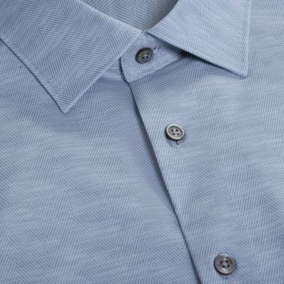 Close-up of the Bugatchi James Herringbone Sport Shirt HF9508K60 in light blue, featuring a collar and three buttons. This wrinkle-resistant Bugatchi shirt blends style and practicality with its subtle herringbone pattern.