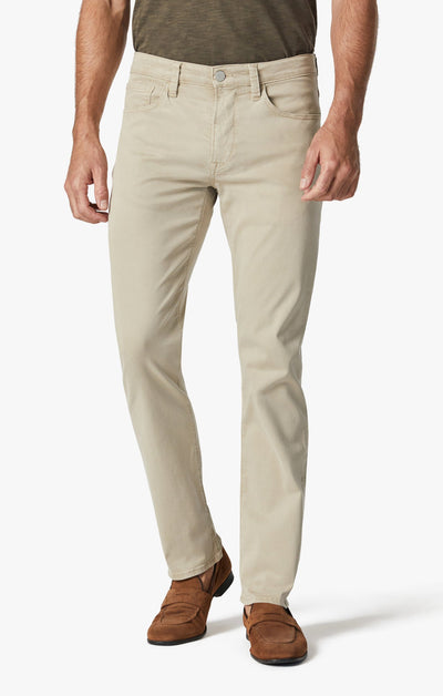 A man wearing 34 Heritage Aluminum Twill pants by 34 Heritage, paired with a green shirt and brown loafers, stands against a white background.