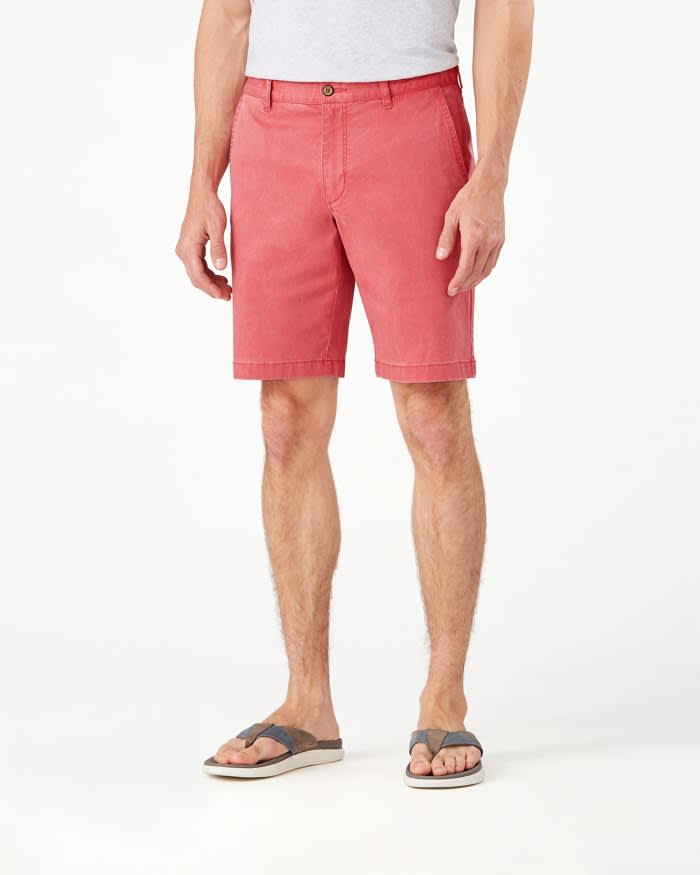 A person wearing a gray t-shirt, gray sandals, and Tommy Bahama Boracay Shorts Big & Tall in salmon pink stands against a white background.
