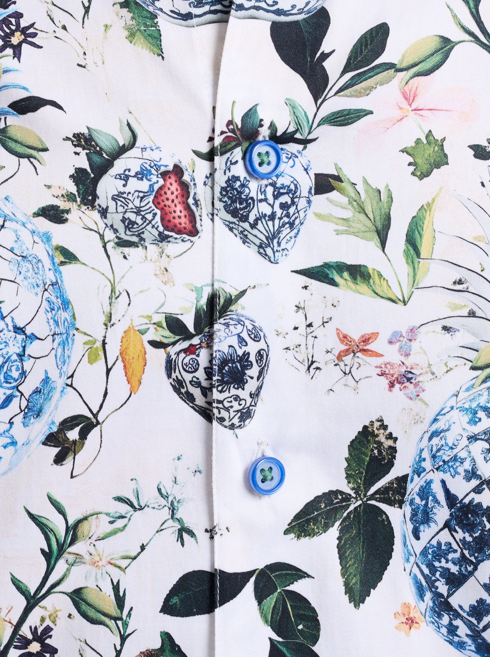 Showcasing the Robert Graham Briarcliff Woven Shirt Big & Tall, this close-up highlights a botanical print with floral and blue porcelain heart motifs accented by green leaves on a crisp white cotton-blend background. The shirt features long sleeves and two distinctive blue buttons, adding a refined touch typical of Robert Graham’s signature style.