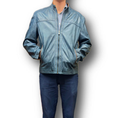 A person wears the Missani Leather Jacket 392834, a blue Italian lambskin piece by Missani, over a blue button-up shirt and matching blue pants, standing with hands in the jacket pockets.