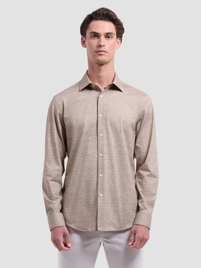 A man stands facing forward against a light gray background, wearing the Bugatchi James Long Sleeve Shirt HF9505K60 in beige and white pants. The shirt, by Bugatchi, is crafted from premium Italian fabrics.