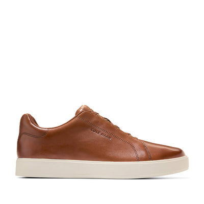 The Cole Haan GrandPro Luxe Slip On Sneaker is a brown leather low-top with a breathable upper, white sole, side stitching, and Cole Haan embossed on the side.
