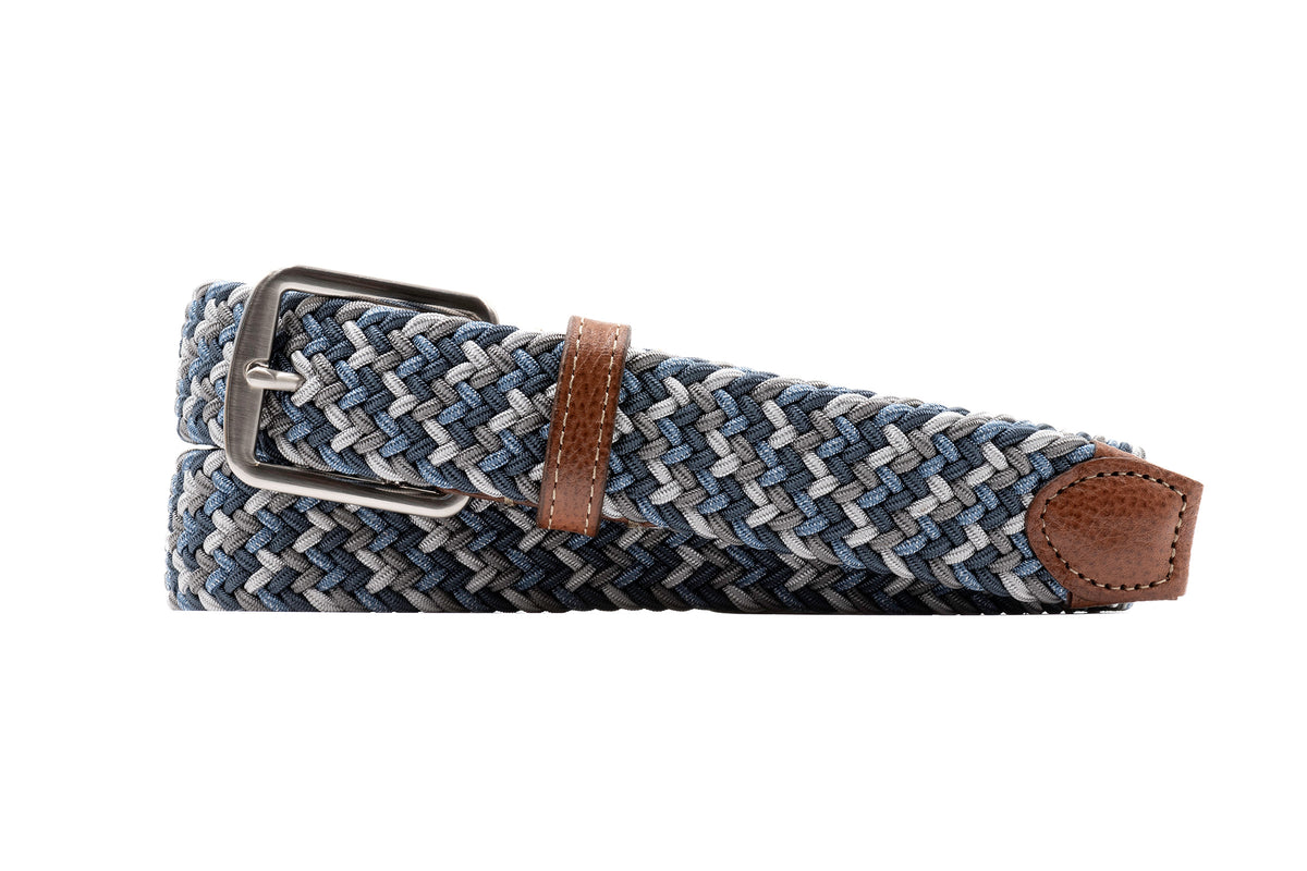 The Martin Dingman Newport Braided Elastic Belt features blue and gray hues, a silver buckle, brown leather accents, and a rectangular leather tip.